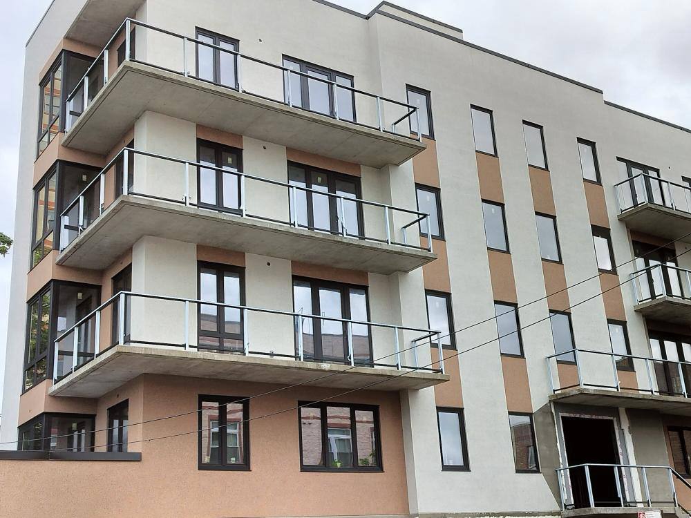 Modern apartment building with multiple balconies and large windows on a beige facade.